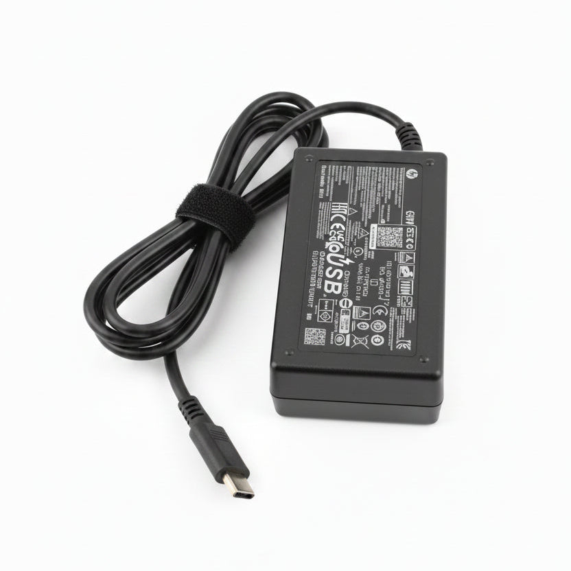 A black 12V 5A laptop power adapter with a coiled black cable, placed on a bright green textured surface.