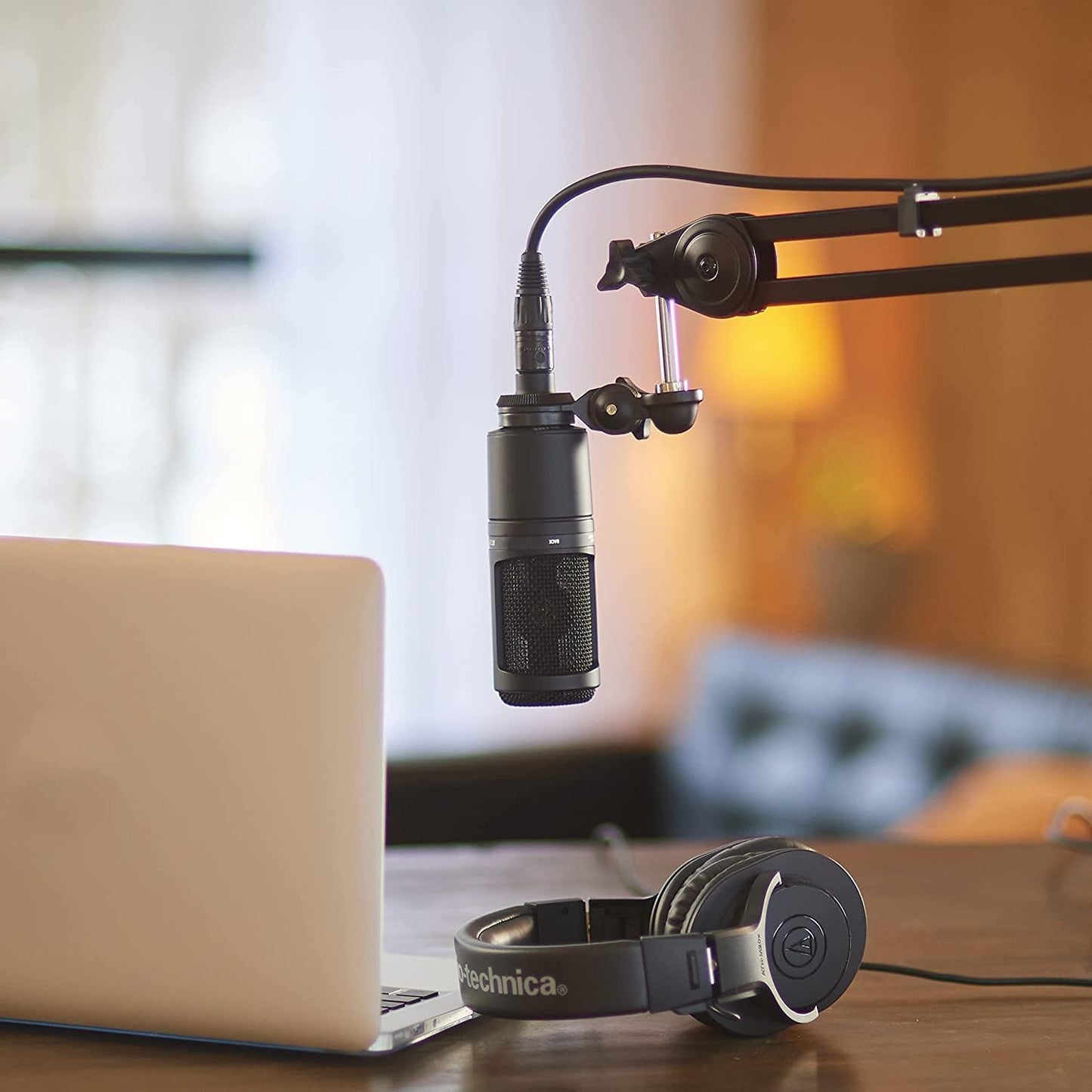 Audio-Technica AT2020 Cardioid Condenser Microphone in sleek black with an XLR connector, set in a professional studio environment.