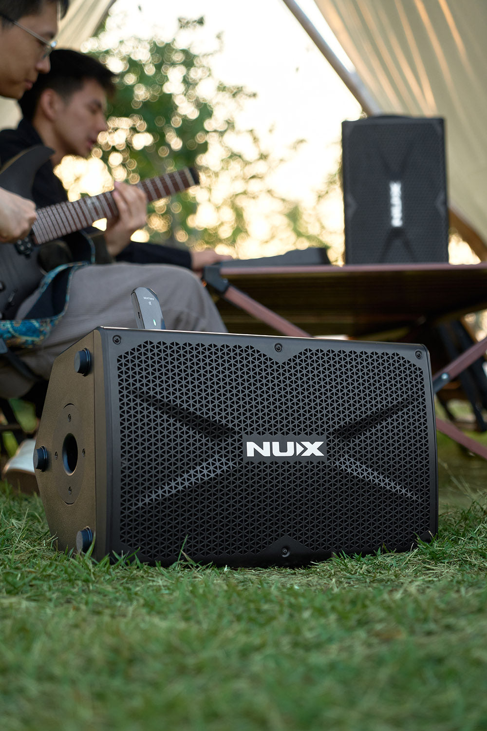 NUX Busking 200FR PA Kenya on grass with front grille visible and guitarist performing in background