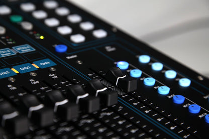Allen Heath Qu-24 Kenya close-up of CH22-24 faders and blue-illuminated mix select buttons on right panel`