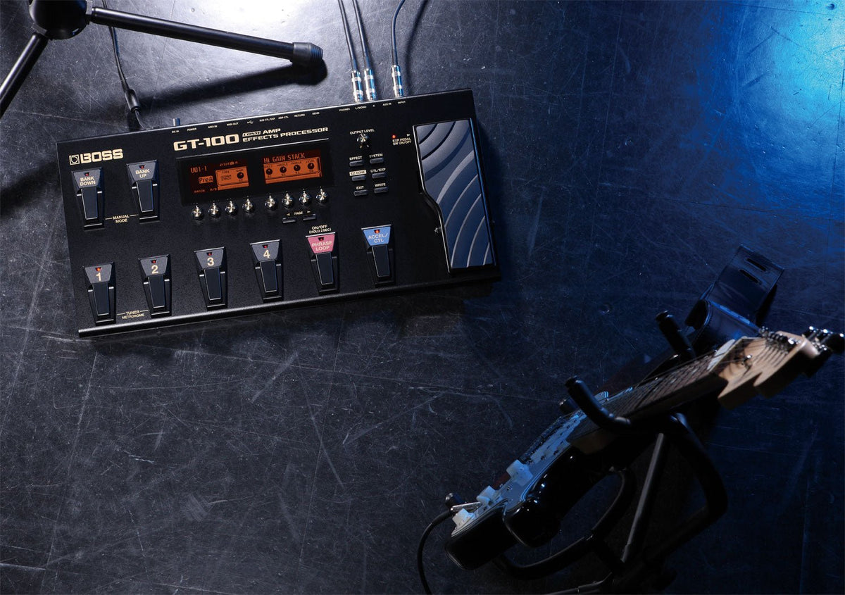 Boss GT-100 Kenya overhead view on dark studio floor with cables connected and electric guitar nearby