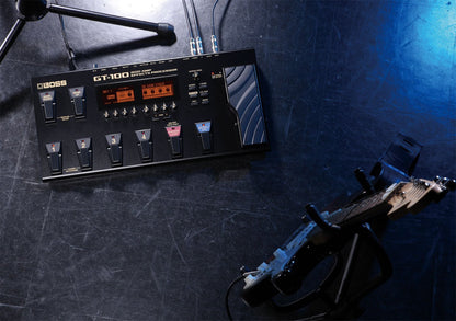 Boss GT-100 Kenya overhead view on dark studio floor with cables connected and electric guitar nearby