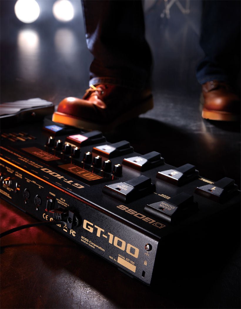Boss GT-100 Kenya on stage floor with performer's foot pressing footswitch under stage lighting