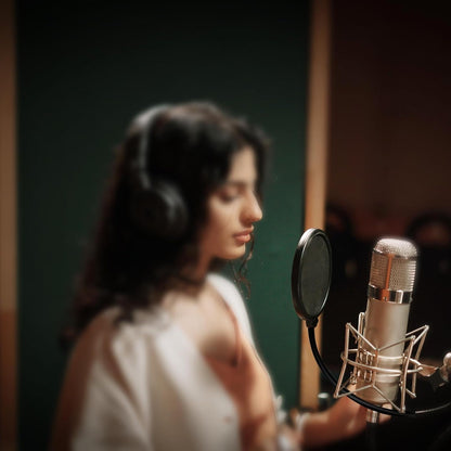 microphone pop filter Kenya in use — vocalist with headphones recording into condenser mic on shock mount in studio