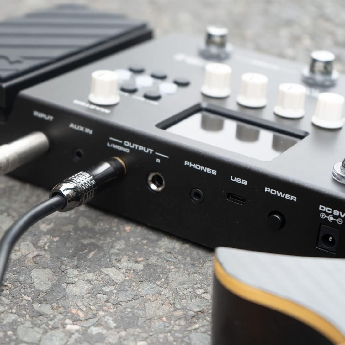 NUX MG-400 guitar processor Kenya in live use on asphalt — guitar cable plugged in, sneaker on expression pedal