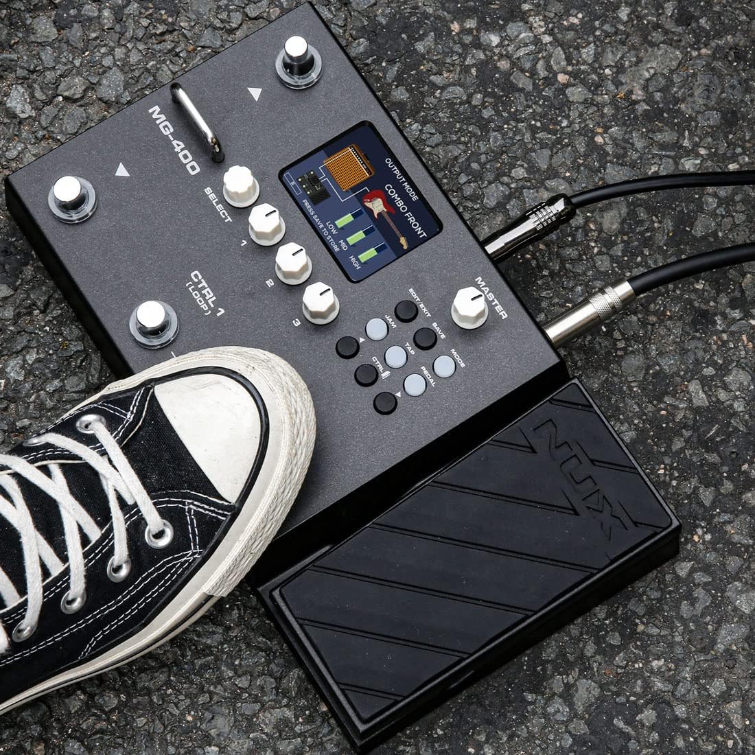 NUX MG-400 guitar processor Kenya in live use on asphalt — guitar cable plugged in, sneaker on expression pedal